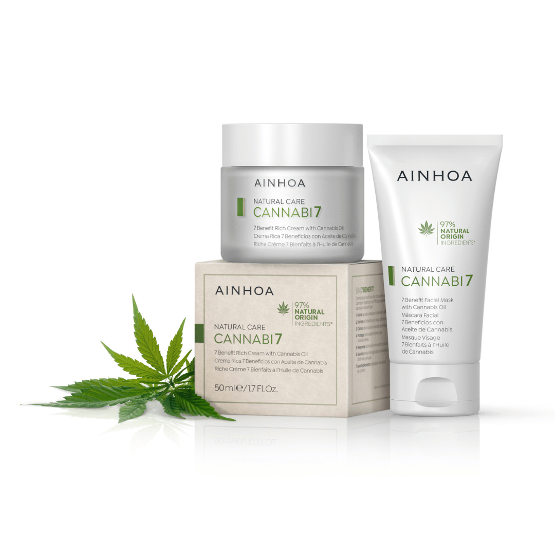 billedet viser den veganske plantebaserede CANNABI7 - 7 BENEFIT RICH CREAM WITH CANNABIS OIL i sin fine hvide glaskrukke sammen med sin æske i pap fra forvaltede skove og den veganske ansigtsmaske med cannabisolie, der alle er udstillet sammen med cannabis blade