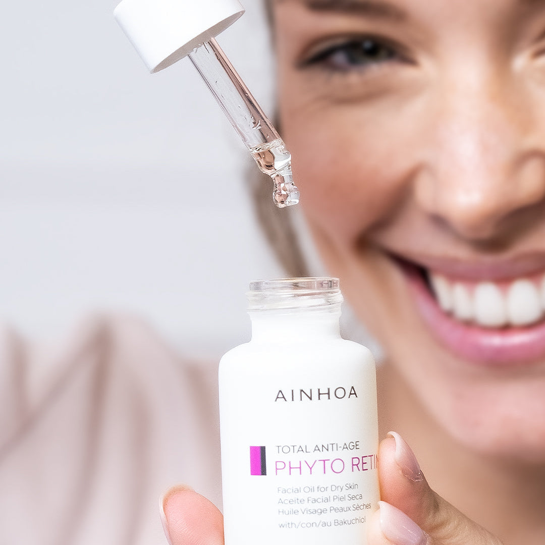 Billedet viser en kvinde der holder en ansigtsolie i hånden og drypper oliedråber fra Ainhoa Phyto Retin+ Facial Oil ned i flasken. Ansigtsolien er vegansk og kraftigt opstrammende olie med bakuchiol for tør og meget tør hud. Nærer, fugter og reducerer rynker.