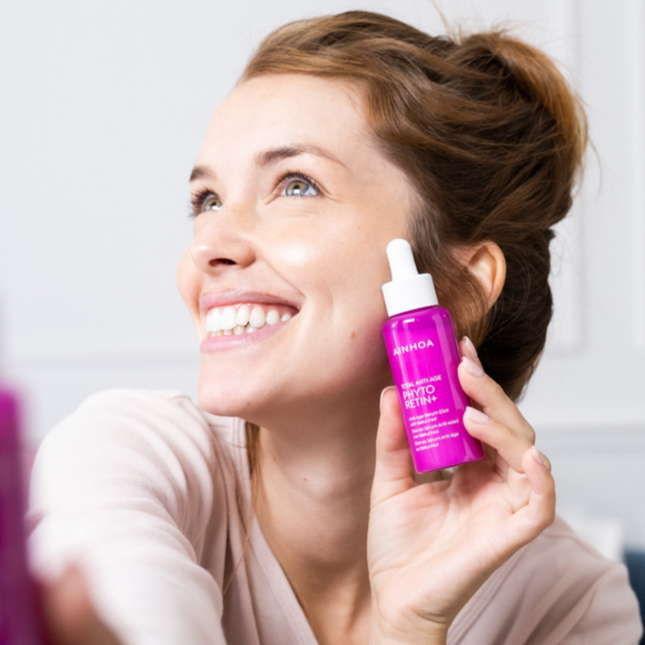 Kvinde der holder hudplejeproduktet Ainhoa Phyto Retin+ Anti-Age Serum: Reducerer synligheden af fine linjer og rynker. Forbedrer hudens fasthed, elasticitet og hydrering. Velegnet til daglig brug. 
