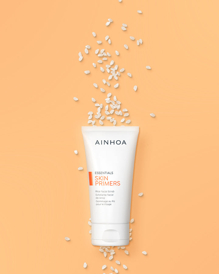 Billedet viser riskorn og Ainhoa Skin Primers Rice Facial Scrub: Naturlig mekanisk peeling med rispulver, risolie og bivoks. Forbedrer hudens glathed og fugt. Ideel til professionelle behandlinger og daglig brug.